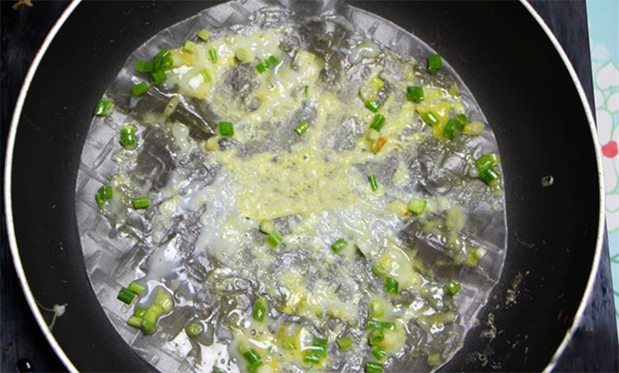 Đập trứng và hành rải đều trên bề mặt bánh