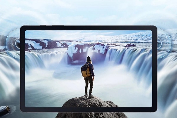 A person standing on a rock looking at a waterfall
Description automatically generated