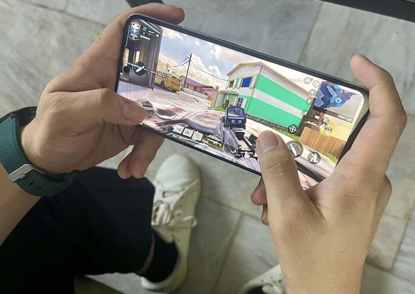 A person holding a phone with a video game on screen
Description automatically generated