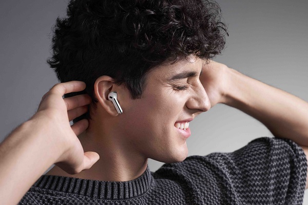 A person holding a silver earbud
Description automatically generated