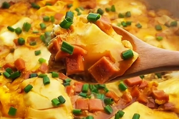 A spoonful of food with green onions

Description automatically generated