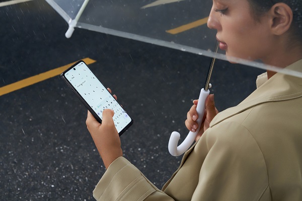 A person holding a phone and an umbrella

Description automatically generated