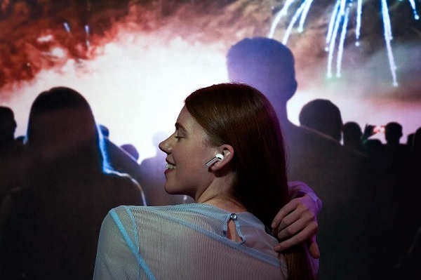 A hand holding a silver wireless earbuds
Description automatically generated