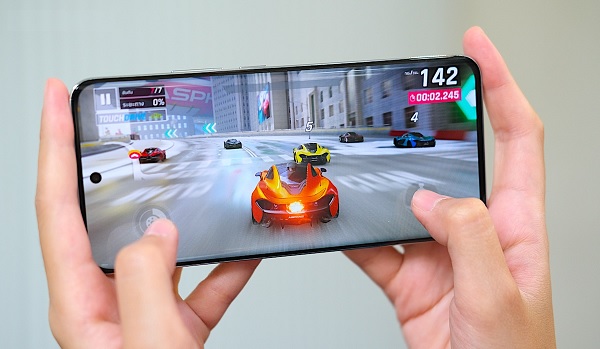 A person holding a cell phone with a video game on screen
Description automatically generated