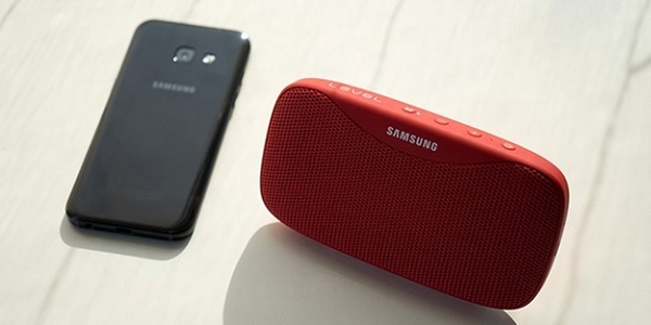A red speaker next to a cell phone

Description automatically generated