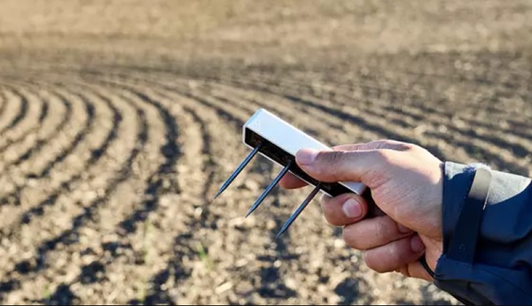 A hand holding a device with spikes in the background

Description automatically generated