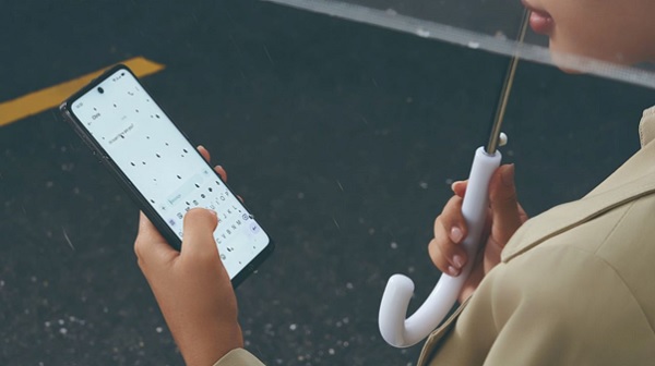 A person holding a phone and an umbrella
Description automatically generated