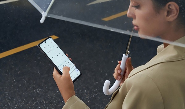 A person holding a phone and an umbrella
Description automatically generated