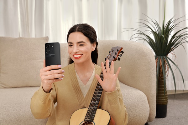 A person holding a phone and a guitar

Description automatically generated