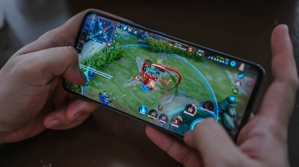 A person holding a cellphone with a video game on screen
Description automatically generated